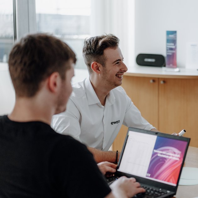 Zwei eworx-Mitarbeiter im Austausch am Laptop